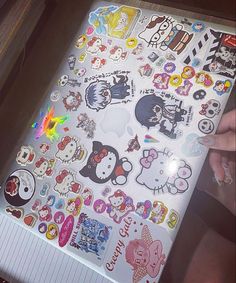 a person holding up a large sheet of stickers with hello kitty designs on it