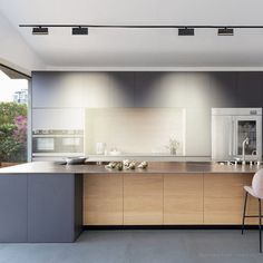 a modern kitchen with an island and bar stools next to the countertop area