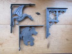 two metal brackets and a dragon on a wooden table with wood grained flooring