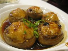 a white bowl filled with meat covered in sauce