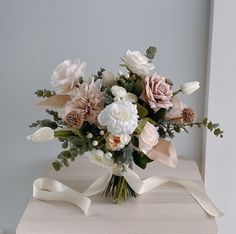 a bouquet of flowers is sitting on top of a table with a ribbon around it