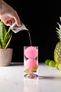 a person pouring water into a glass filled with fruit