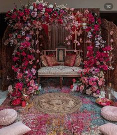 a room filled with lots of pink flowers and pillows on top of a colorful rug