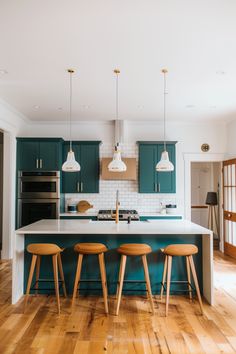 three stools sit in front of an island with four lights hanging from the ceiling