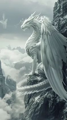 a white dragon sitting on top of a mountain next to a bird in the sky