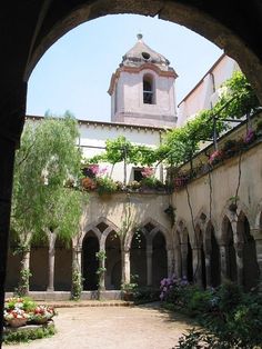 an arched doorway leads into a courtyard with flowers and greenery