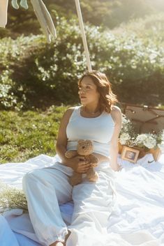 a woman sitting on a blanket holding a teddy bear