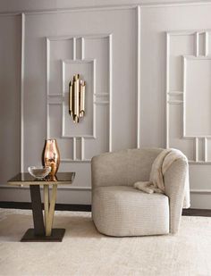 an elegant living room with white walls and gold accents on the wall, along with a beige chair