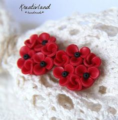 two red flowers are sitting on top of a white piece of lace with black buttons