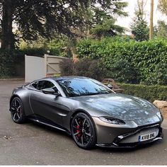 a grey sports car parked in front of some bushes