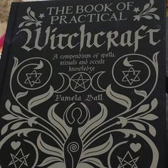 the book of practical witchcraft is being held up by a person's hand