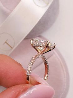 a close up of a person's hand holding an engagement ring