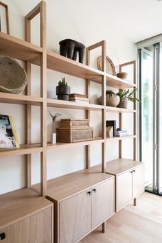 a wooden shelf filled with lots of books and vases next to a glass door