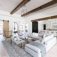 a living room filled with furniture and a chandelier hanging over the top of it