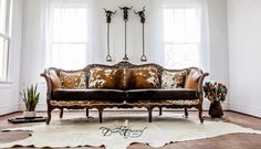 a couch sitting in front of two windows on top of a wooden floor next to a cowhide rug