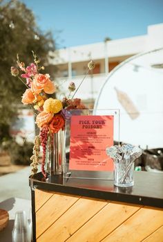 a table topped with vases filled with flowers next to an orange sign that says i love you