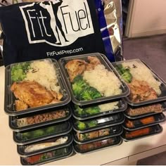 six plastic containers filled with food on top of a white table next to a black bag