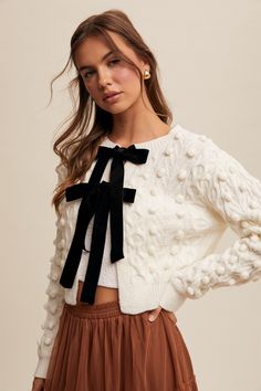 S and M are currently in stock. Pre-Order Now Available for size L, ships approximately one week after purchase. Sophistication meets femininity in the James Velvet Bow Tie Cardigan. This statement-making style features a classic cream cable knit cardi with a delicate black velvet bow tie closure. Slightly cropped, but not too short. This length makes it perfect for layering over your favorite dress or with you favorite high waisted jeans. To the office, to dinner, this transitional piece piece Velvet Bow Tie, Black Velvet Bow, Velvet Tie, Knit Cardi, Barbie Outfits, Formal Dress Shops, Cable Knit Cardigan, Velvet Bow, Sweater Sale