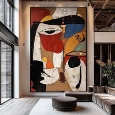 an abstract painting hangs in the middle of a large room with couches and tables