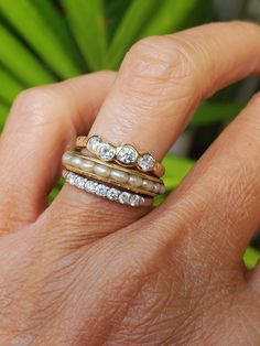 a woman's hand with three different rings on her finger and the other ring has diamonds in it