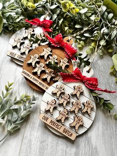 two wooden christmas ornaments with red bows and greenery on the table next to them