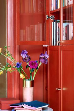 a vase filled with flowers sitting on top of a table next to a book shelf