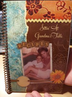 a hand holding up a scrapbook with an image of a woman and child on it