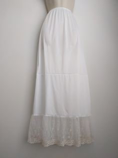 "An exquisite accessory for your wardrobe, this feminine underskirt slip worn with your skirt or dress will make you feel very special! It is made of white nylon with elastic waistband and 7 inches embroidered very soft ivory lace ruffle trim. This accessory makes a perfect gift! Hand wash in cold water. Available in sizes: XS-0-2, Waist: 24 1/2\", Hip: 35\" S-4-6, Waist: 25 1/2\"-26 1/2\", Hip: 36-37\" M-8-10, Waist: 27 1/2-28 1/2\", Hip: 38-39\" L-12-14, Waist: 30-31 1/2\", Hip: 40 1/2-42\" XL Feminine Cream Skirt With Lace Trim, White Floral Embroidery Skirt For Wedding, White Floral Embroidered Skirt For Wedding, White Floral Embroidered Wedding Skirt, Fitted Summer Skirt With Delicate Lace, Fitted Delicate Lace Skirt For Summer, Summer Fitted Skirt With Delicate Lace, White Delicate Lace Skirt For Summer, Feminine Long Skirt With Lace Trim