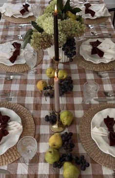 the table is set with plates, silverware and fruit for an elegant centerpiece