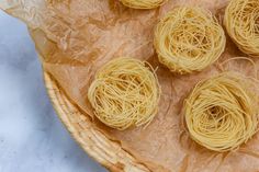 four pieces of noodles are sitting in a wicker basket on top of wax paper