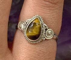 This listing is for a single 925 Teardrop Swirl Tigers Eye Sterling Silver Ring.  A few options are pictured to show the natural variation in the stone.  Tiger's Eye is an opaque stone that has a honey yellow to red brown hue. It is typically seen with bands of a silky luster running parallel through the stone. This stone was found in the early 1800's in South Africa. Tiger's Eye is named because of the similarity to the eye of a tiger. Tiger's Eye helps you understand your own needs, especially in relation to others. Due to its appearance, it is thought to be all seeing. It has been used to focus the mind, making decisions unclouded by emotions, therefore, Tiger's Eye represents Clear Thinking and Understanding. Solar Chakra: The Solar Plexus Chakra brings energy and confidence to everyda Solar Chakra, Tigers Eye Ring, Honey Yellow, Making Decisions, Clear Thinking, Solar Plexus Chakra, Solar Plexus, Eye Ring, Stackable Ring