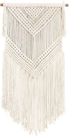 a white wall hanging with tassels and fringes on the top of it