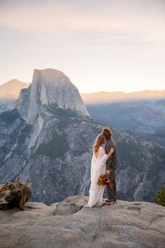 a bride and groom standing on top of a mountain