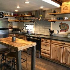 a kitchen with wooden cabinets and stainless steel appliances is pictured in this image, there are two stools at the center of the counter