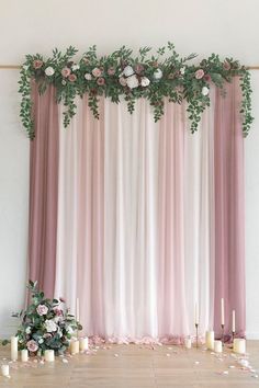 a pink and white wedding backdrop with candles, flowers and greenery on the floor