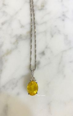 Metal: 14kt White Gold Stone: Yellow Sapphire And Diamond Stone Shapes: Round And Oval-Shape Yellow Sapphire Weight: 3.27 ctw, 9.84 x 7.82 mm Diamond Weight: .08 ctw, round diamonds Measurements Of Pendant From Bail To Bottom Of Pendant: 19.93 mm Weight of entire piece with chain: 2.50 grams Type of Chain: 1.2mm Diamond-cut Singapore Chain Length of Chain: 16 Inches Type of Lock: Spring Ring Note: Other chain styles and lengths available. Pendant can also be sold without chain. Please inquire if Formal Oval Necklace With Accent Stones, Elegant Yellow Marquise Jewelry, Luxury Yellow Oval Necklaces, Yellow Marquise Fine Jewelry, Gold Oval Gemstones With Brilliant Cut, Luxury Yellow Oval Necklace, Fine Yellow Oval Jewelry, Elegant Yellow Oval Gemstones, Yellow Oval Cabochon Gemstone Jewelry