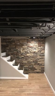 an empty room with stone walls and white stairs leading up to the second floor area