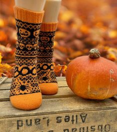 two pairs of socks sitting on top of a wooden box next to a pumpkin and some leaves