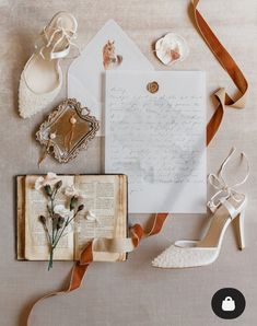 an assortment of wedding accessories including shoes, ring and letter on top of a table