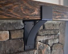 the corner of a stone fireplace with a metal shelf on it's side and a wood paneled mantle