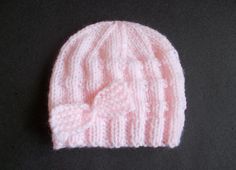 a pink knitted hat sitting on top of a black table next to a pair of scissors