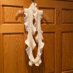 a white crocheted sweater hanging from a hook on a wooden door with wood paneling