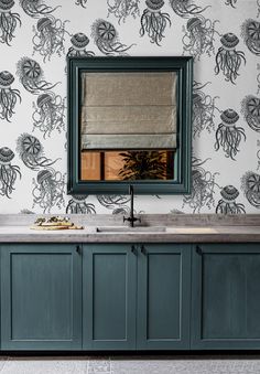 a bathroom with blue cabinets and wallpaper that has an octopus design on it, along with a large mirror above the sink