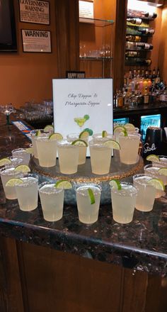 there are many glasses on the bar with limes in them and a sign that says happy margarita's