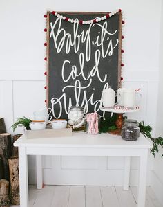 a white table topped with cake and candles next to a chalkboard that says baking it's called christmas