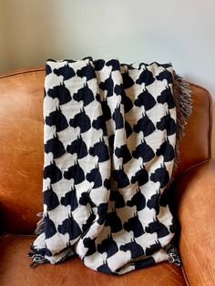 a black and white blanket sitting on top of a brown couch