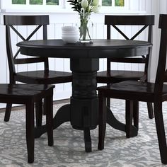 a dining table with four chairs and a vase on top of it in front of a window