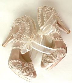 two pairs of high heeled shoes with lace and pearls on the toes, tied together