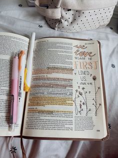 an open book with writing on it next to a pink pen and white polka dot bag