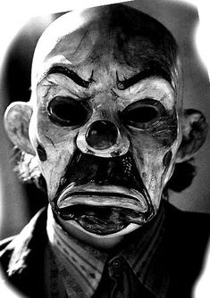 a black and white photo of a man wearing a creepy mask